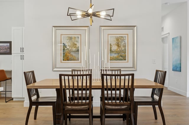 dining space featuring light wood-type flooring, baseboards, and a chandelier