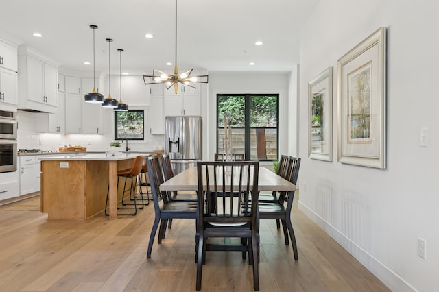 dining room featuring recessed lighting, light wood-style flooring, a chandelier, and baseboards