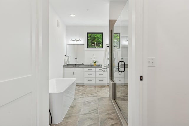 bathroom featuring marble tiled flooring, a stall shower, vanity, a freestanding tub, and recessed lighting