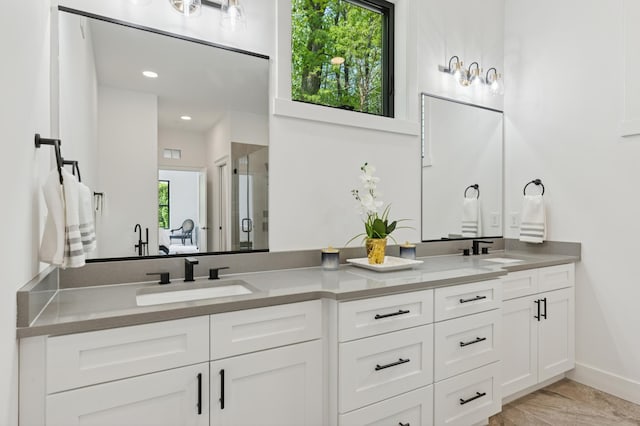 full bath featuring double vanity, a shower stall, and baseboards