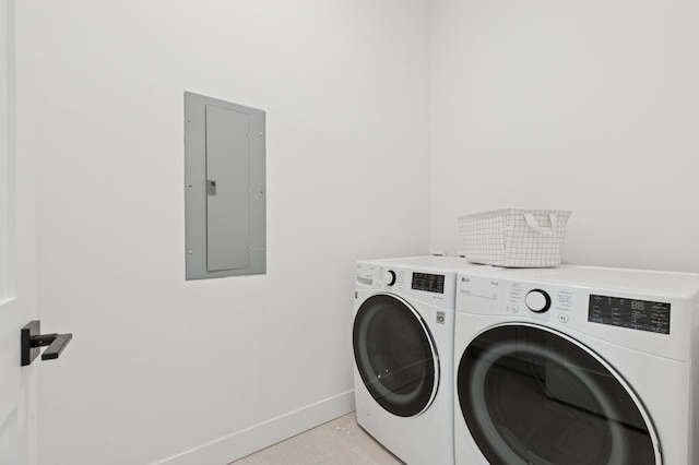clothes washing area featuring electric panel, separate washer and dryer, and baseboards