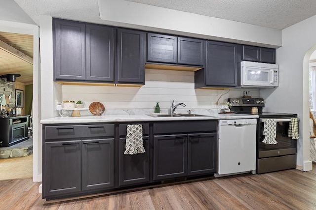 212 4, Montevideo, MN 56265 - kitchen with white appliances, a sink, dark wood-type flooring, arched walkways, and light countertops