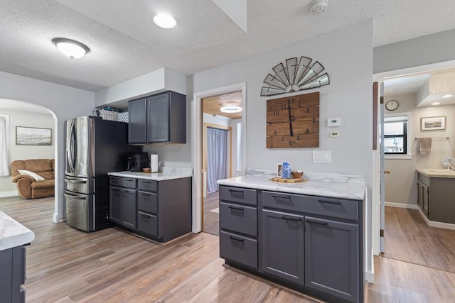 212 4, Montevideo, MN 56265 - kitchen with a textured ceiling, freestanding refrigerator, light wood finished floors, arched walkways, and a sink