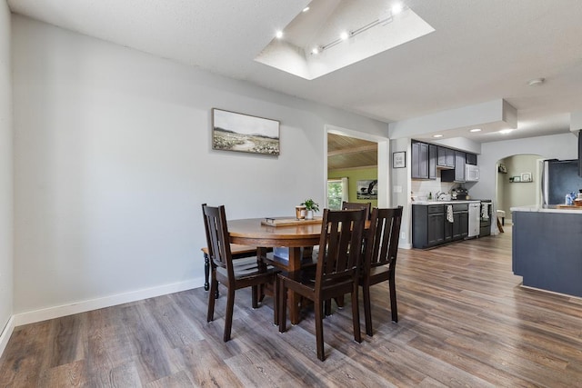 212 4, Montevideo, MN 56265 - dining room featuring arched walkways, dark wood finished floors, a skylight, baseboards, and recessed lighting