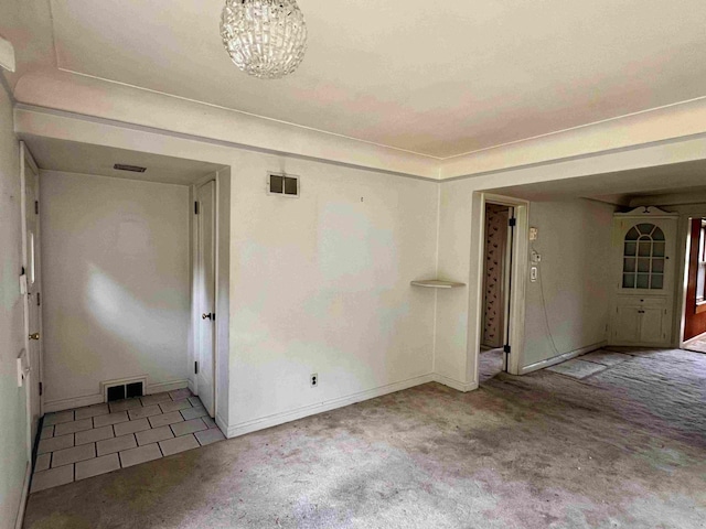 carpeted empty room featuring baseboards and a chandelier