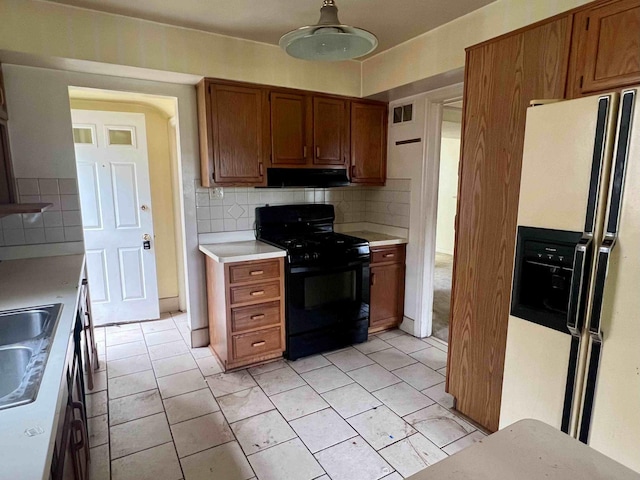 kitchen with gas stove, white refrigerator with ice dispenser, light countertops, under cabinet range hood, and brown cabinetry
