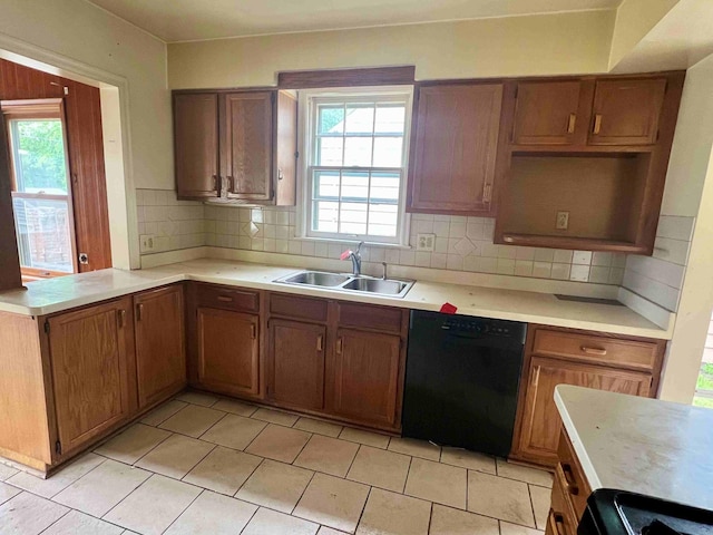 kitchen with black dishwasher, a sink, light countertops, and backsplash