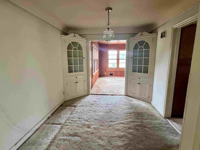 unfurnished dining area featuring carpet, baseboards, and a chandelier