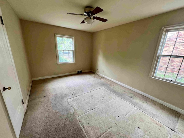 carpeted spare room with healthy amount of natural light, ceiling fan, and baseboards