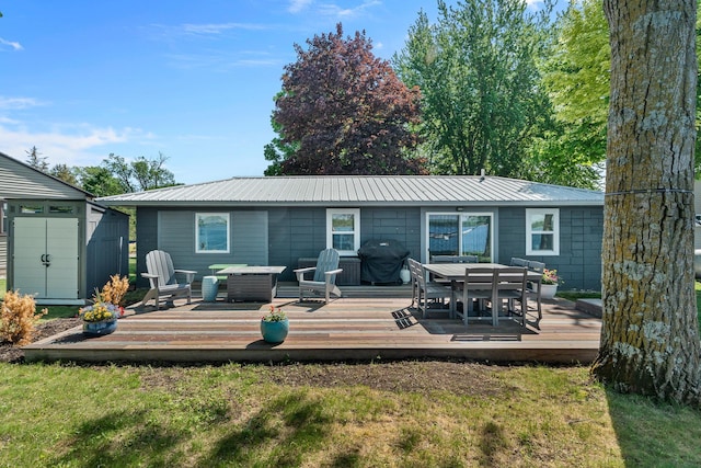 46710 Glens Beach Rd, Elysian Twp, MN 56096 - back of house featuring outdoor dining space, metal roof, a deck, and a lawn