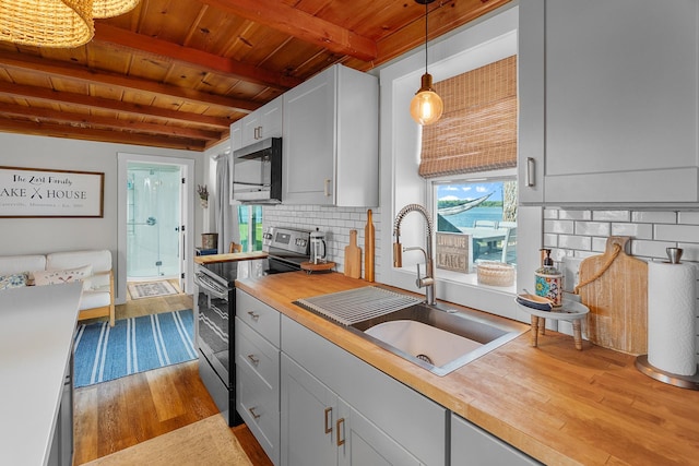 46710 Glens Beach Rd, Elysian Twp, MN 56096 - kitchen featuring appliances with stainless steel finishes, a sink, wooden ceiling with exposed beams, dark wood-style floors, and butcher block counters
