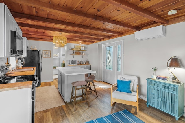 46710 Glens Beach Rd, Elysian Twp, MN 56096 - kitchen with a wall mounted AC, range with electric cooktop, wood ceiling with exposed beams, light wood-style flooring, and a center island