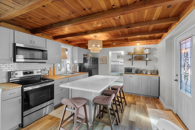 46710 Glens Beach Rd, Elysian Twp, MN 56096 - kitchen featuring stainless steel appliances, a sink, wood ceiling with exposed beams, light wood finished floors, and decorative backsplash