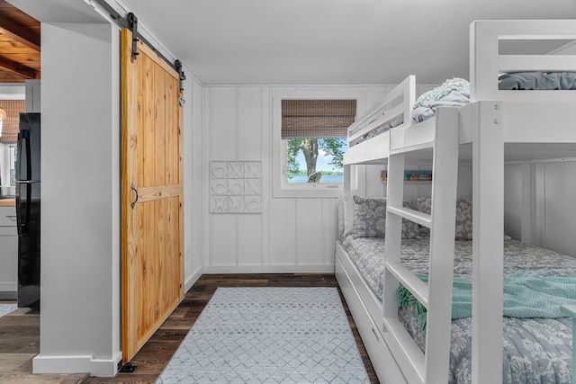 46710 Glens Beach Rd, Elysian Twp, MN 56096 - bedroom featuring a barn door, dark wood-style floors, and freestanding refrigerator