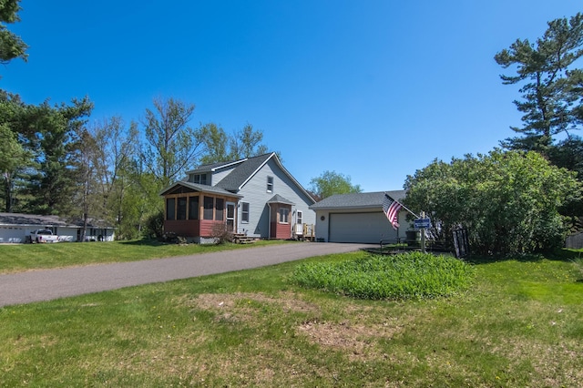 207 2nd Ave W, Balsam Lake, WI 54810 - view of front of home with asphalt driveway, a garage, a front lawn, and a sunroom