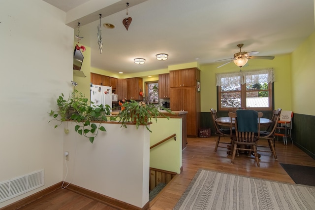207 2nd Ave W, Balsam Lake, WI 54810 - kitchen with white appliances, a peninsula, brown cabinetry, wood finished floors, and ceiling fan