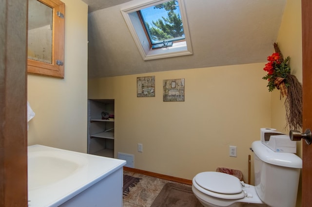 207 2nd Ave W, Balsam Lake, WI 54810 - half bathroom with toilet, a skylight, vaulted ceiling, vanity, and baseboards