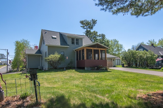 207 2nd Ave W, Balsam Lake, WI 54810 - view of front facade featuring a sunroom, a front yard, a shingled roof, and a garage