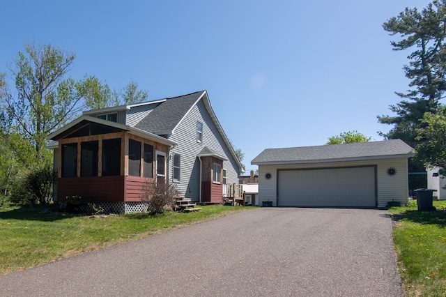 207 2nd Ave W, Balsam Lake, WI 54810 - view of front of property featuring a sunroom, a detached garage, an outdoor structure, a front lawn, and a shingled roof