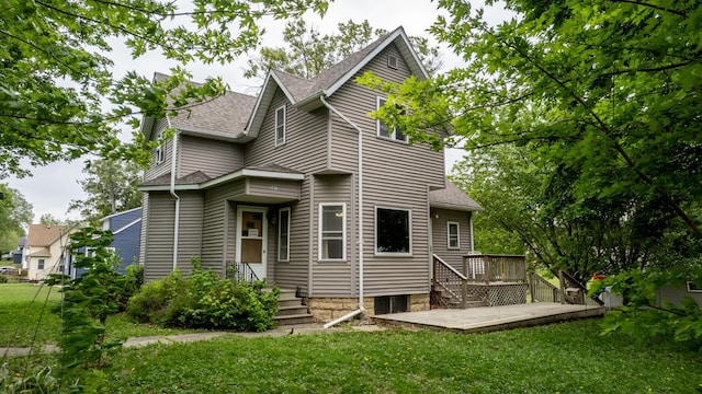 back of property with a lawn, a deck, a shingled roof, and a patio area