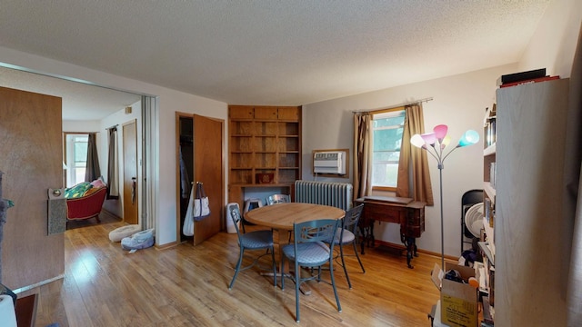 dining area with light wood-style flooring, radiator, a textured ceiling, and baseboards