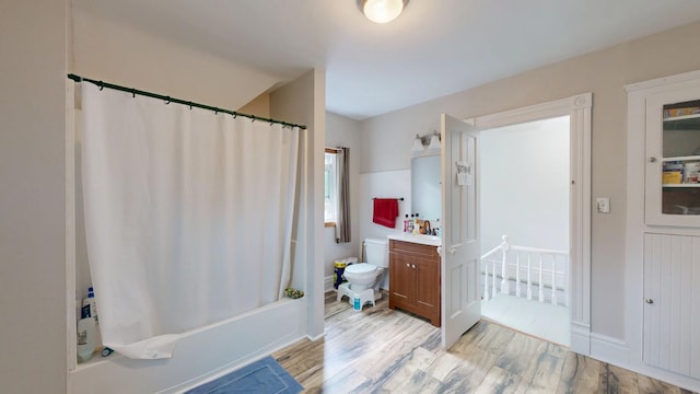 bathroom with wood finished floors, vanity, shower / tub combo with curtain, toilet, and baseboards