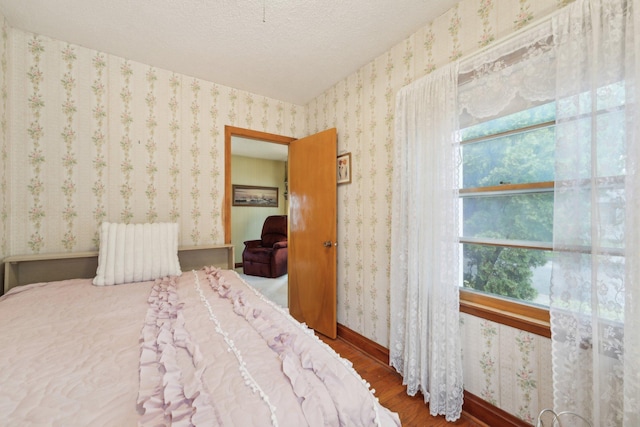 4518 Colfax Ave N, Minneapolis, MN 55412 - bedroom featuring wood finished floors, wallpapered walls, multiple windows, baseboards, and a textured ceiling