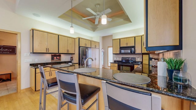 2592 Aspen Pl SW, Rochester, MN 55902 - kitchen featuring black appliances, a tray ceiling, ceiling fan, a peninsula, and light wood-style floors