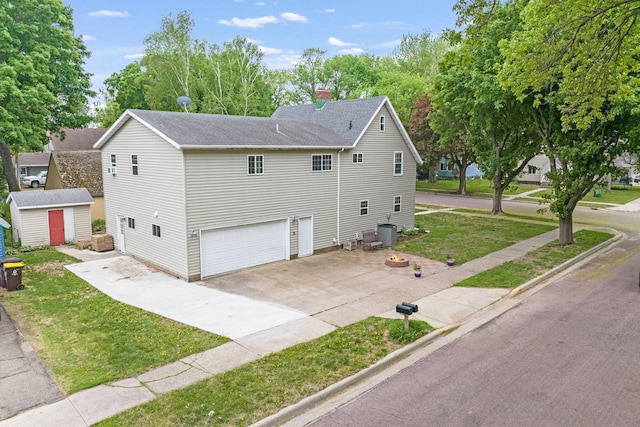 114 3rd Ave E, Truman, MN 56088 - view of front facade with concrete driveway, an attached garage, a storage unit, a front yard, and a shingled roof