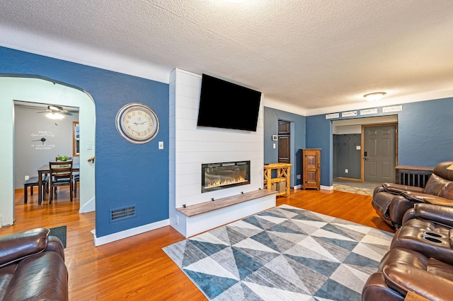 114 3rd Ave E, Truman, MN 56088 - living area featuring a textured ceiling, wood finished floors, a large fireplace, arched walkways, and a textured wall