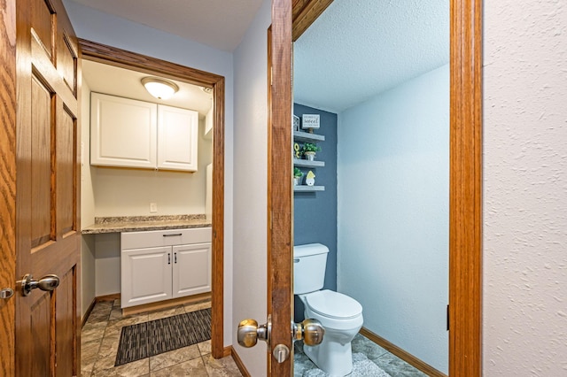 114 3rd Ave E, Truman, MN 56088 - bathroom with toilet, baseboards, and a textured ceiling