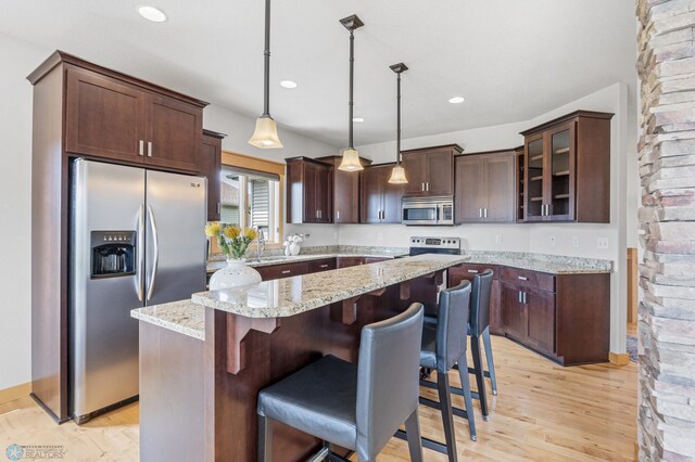 405 12th St NE, Dilworth, MN 56529 - kitchen featuring stainless steel appliances, a kitchen island, dark brown cabinets, light wood-style floors, and glass insert cabinets