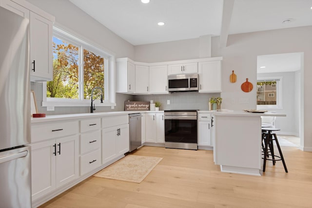 309 Shore Dr, Forest Lake, MN 55025 - kitchen featuring appliances with stainless steel finishes, decorative backsplash, white cabinetry, light wood-style flooring, and light countertops
