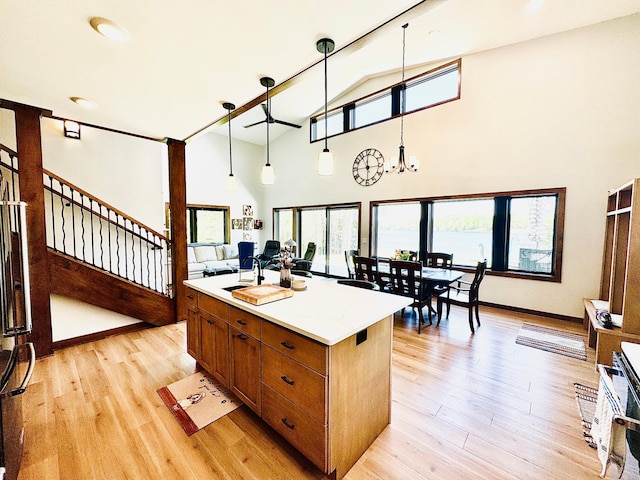 30710 County Road 45, Marcell Twp, MN 56628 - kitchen featuring brown cabinetry, light wood-style flooring, high vaulted ceiling, a kitchen island, and light countertops