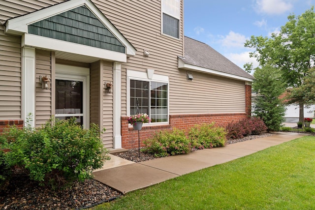 13900 Garnet Ter NW, Ramsey, MN 55303 - view of exterior entry with brick siding, a lawn, and a shingled roof