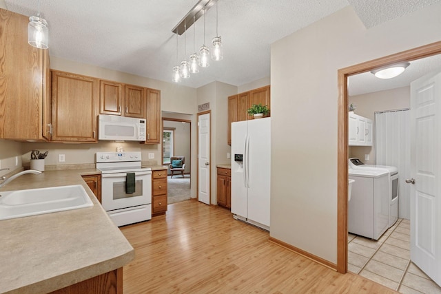 13900 Garnet Ter NW, Ramsey, MN 55303 - kitchen featuring white appliances, washer and clothes dryer, light wood finished floors, light countertops, and pendant lighting