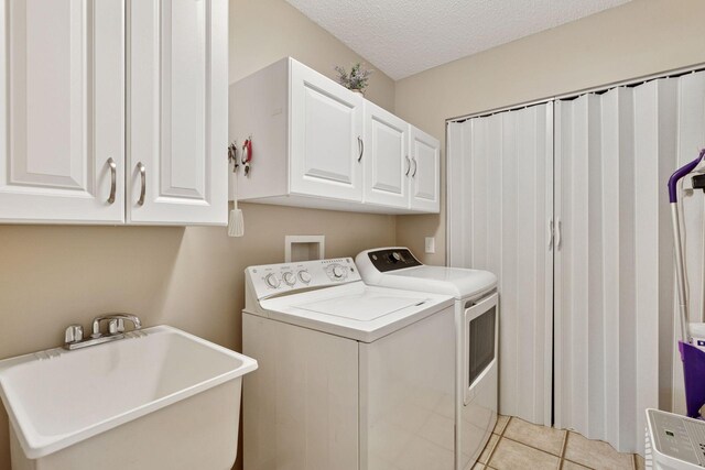 13900 Garnet Ter NW, Ramsey, MN 55303 - washroom with separate washer and dryer, cabinet space, a textured ceiling, and light tile patterned flooring