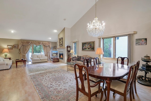 8207 Norman Creek Trl, Bloomington, MN 55437 - dining room with high vaulted ceiling, a glass covered fireplace, a chandelier, light wood finished floors, and recessed lighting
