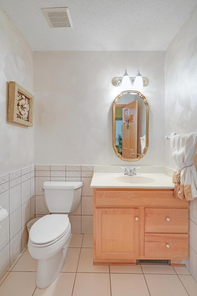 8207 Norman Creek Trl, Bloomington, MN 55437 - bathroom with toilet, vanity, a textured ceiling, tile walls, and tile patterned floors