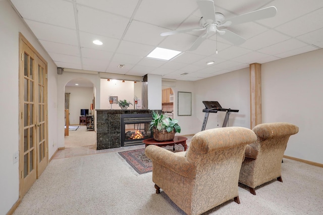 8207 Norman Creek Trl, Bloomington, MN 55437 - living room featuring arched walkways, a drop ceiling, a tile fireplace, baseboards, and a ceiling fan