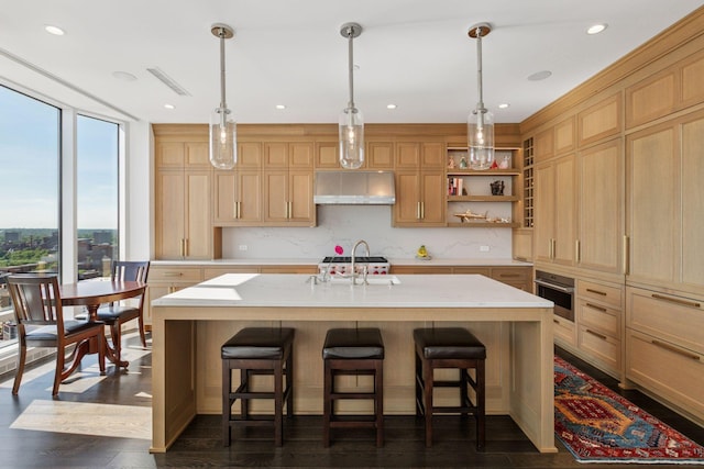 1111 River Pkwy Unit 24C, Minneapolis, MN 55415 - kitchen featuring light brown cabinetry, a sink, exhaust hood, light countertops, and a breakfast bar