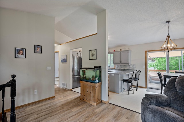 604 Brookview Ln SW, Isanti, MN 55040 - living area with a chandelier, light wood finished floors, baseboards, and vaulted ceiling