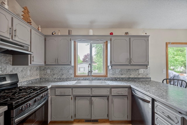 604 Brookview Ln SW, Isanti, MN 55040 - kitchen featuring appliances with stainless steel finishes, a sink, under cabinet range hood, a textured ceiling, and gray cabinetry