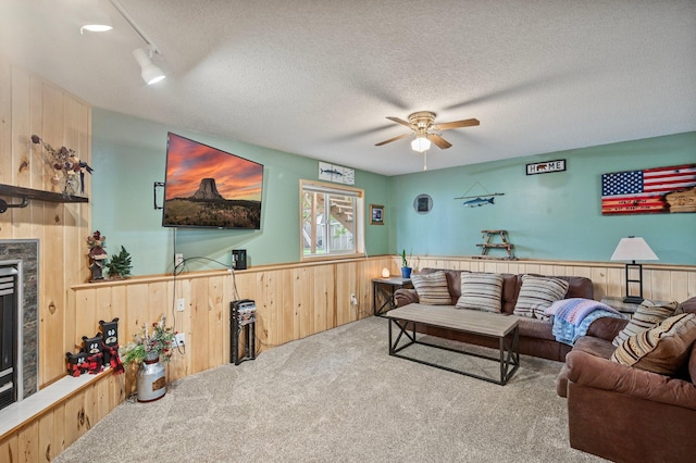 604 Brookview Ln SW, Isanti, MN 55040 - carpeted living area with wooden walls, ceiling fan, wainscoting, a textured ceiling, and a glass covered fireplace