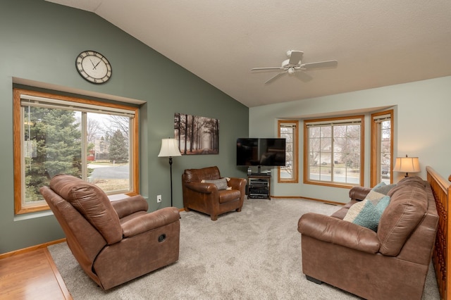 living area with lofted ceiling, ceiling fan, plenty of natural light, and baseboards