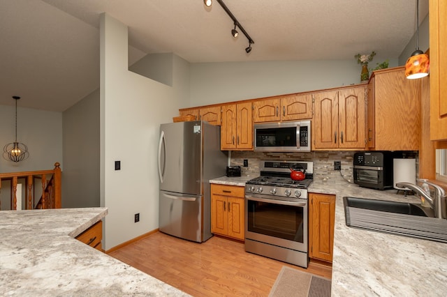 kitchen featuring stainless steel appliances, lofted ceiling, a sink, backsplash, and light countertops
