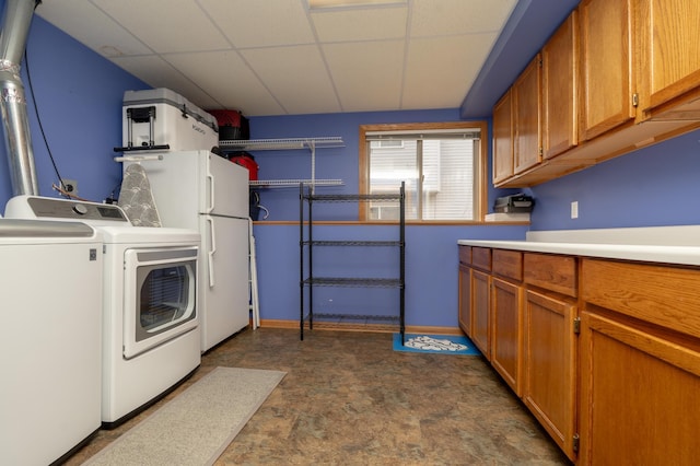 clothes washing area with washing machine and dryer, cabinet space, and baseboards