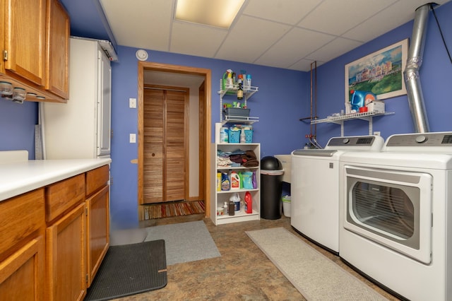 clothes washing area featuring washer and dryer and cabinet space