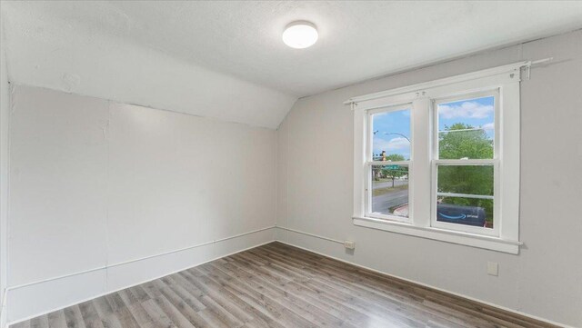 1001 Washington Memorial Dr, Saint Cloud, MN 56301 - additional living space featuring vaulted ceiling, wood finished floors, baseboards, and a textured ceiling