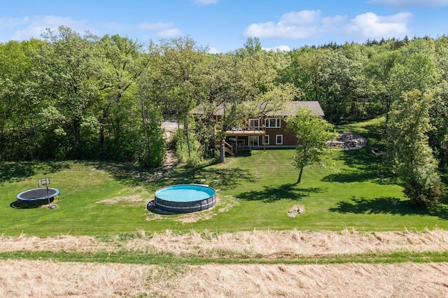 8259 Barton Ave NW, Buffalo, MN 55313 - view of green lawn featuring a view of trees, a wooden deck, and a trampoline
